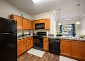 Thumbnail 27 of 39 - A kitchen with wooden cabinets and black appliances.