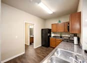 Thumbnail 28 of 39 - A kitchen with a black refrigerator and wooden cabinets.