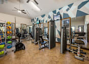 Thumbnail 11 of 39 - A gym with a variety of equipment including weights and machines.