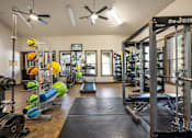 Thumbnail 10 of 39 - A gym with a variety of equipment including dumbbells, weight plates, and a bench press.