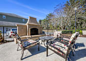 Thumbnail 17 of 39 - A patio with a fireplace, chairs and a table.