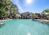 Thumbnail 13 of 39 - A large swimming pool in front of a house with a sunny sky above.