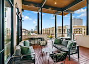 Thumbnail 19 of 26 - A wooden balcony with a table and chairs overlooking a city skyline.
