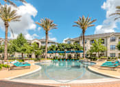 Thumbnail 20 of 28 - A swimming pool surrounded by palm trees and lounge chairs.