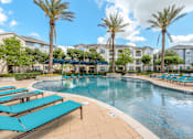 Thumbnail 21 of 28 - A swimming pool surrounded by sun loungers and palm trees.
