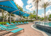Thumbnail 23 of 28 - A pool area with sun loungers and a blue canopy.