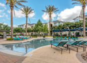 Thumbnail 22 of 28 - A pool surrounded by palm trees and lounge chairs.