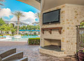 Thumbnail 24 of 28 - A patio with a stone fireplace and a television mounted on the wall.