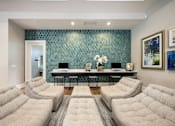 Thumbnail 9 of 47 - A living room with a grey sofa and a table with a vase of flowers on it.