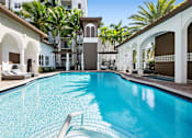 Thumbnail 4 of 40 - A swimming pool in a resort with a white building in the background.