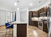 Thumbnail 5 of 34 - A kitchen with a white island and blue chairs.