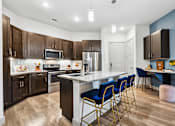 Thumbnail 4 of 34 - A kitchen with a white island and blue chairs.