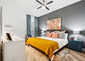 Thumbnail 6 of 34 - A bedroom with a bed, nightstand, and lamp.
