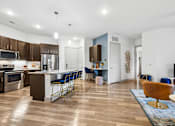 Thumbnail 3 of 34 - A modern kitchen with a dining area and a living room.