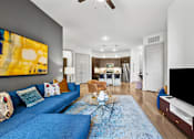 Thumbnail 2 of 34 - A living room with a blue couch and a painting on the wall.
