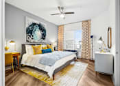 Thumbnail 10 of 34 - A bedroom with a bed, a desk, and a ceiling fan.