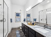 Thumbnail 7 of 34 - A bathroom with a walk-in shower, a sink, and a mirror.