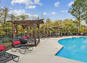 Thumbnail 20 of 45 - A pool area with a wooden pergola and lounge chairs.
