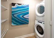 Thumbnail 9 of 25 - a laundry room with a washing machine and a painting on the wall