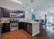 Thumbnail 19 of 29 - an open kitchen and living room with a large island and stainless steel appliances