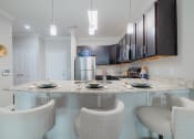Thumbnail 20 of 29 - a kitchen with a granite counter top and a bar with three chairs