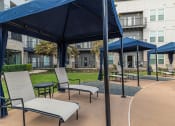 Thumbnail 16 of 29 - a patio with chairs and umbrellas in front of an apartment building