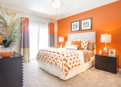 Thumbnail 8 of 19 - a bedroom with an orange accent wall and a bed