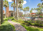 Thumbnail 12 of 19 - a pathway leading to a swimming pool with palm trees