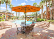 Thumbnail 18 of 19 - a patio with a table and chairs under an orange umbrella