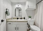 Thumbnail 9 of 38 - A white bathroom with a marble countertop and a round mirror.