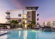 Thumbnail 28 of 45 - a luxury apartment building with a pool at dusk