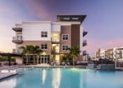 Thumbnail 26 of 45 - a luxury apartment building with a pool at dusk