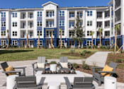Thumbnail 43 of 47 - A large building with a blue and white exterior is surrounded by a courtyard with multiple chairs and tables.