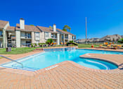 Thumbnail 51 of 61 - A swimming pool surrounded by a brick patio and apartment buildings.