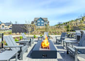 Thumbnail 18 of 30 - A fire pit in the middle of a patio surrounded by chairs.