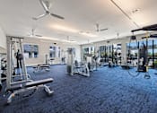 Thumbnail 20 of 33 - A spacious gym with a variety of equipment including treadmills, weights, and exercise machines.