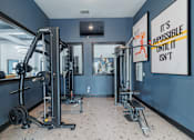 Thumbnail 16 of 39 - A gym with a mirror, weight machines, and a motivational poster.