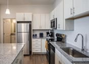 Thumbnail 39 of 45 - a kitchen with granite counter tops and a stainless steel refrigerator