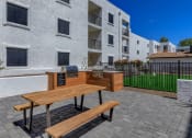 Thumbnail 15 of 22 - furnished patio with picnic table and grilling area at vela on the avenue apartments