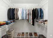 Thumbnail 24 of 33 - A white closet with clothes and shoes.