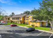 Thumbnail 6 of 67 - a large yellow house with cars parked in a parking lot