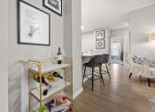Thumbnail 17 of 67 - a living room and dining room with white walls and a gold shelf with wine glasses