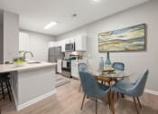Thumbnail 12 of 67 - a dining room with a table and chairs and a kitchen with a sink and microwave
