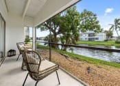 Thumbnail 28 of 41 - a balcony with a wicker chair and a view of a body of water