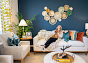 Thumbnail 20 of 32 - A woman is sitting on a white couch with a book in front of her.