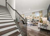 Thumbnail 13 of 32 - A staircase with a metal railing leads to a living room with a couch and a coffee table.
