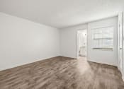 Thumbnail 8 of 29 - an empty living room with wood flooring and a door to a bathroom