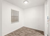 Thumbnail 9 of 29 - an empty room with a window and wood flooring