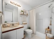 Thumbnail 3 of 48 - A bathroom with a white toilet, sink, and shower area.