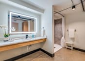 Thumbnail 21 of 40 - A bathroom with a large mirror and a white sink.